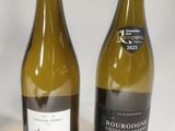 two bottles of white wine sitting next to each other on a table