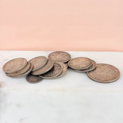 a pile of coins sitting on a table next to a bottle of beer