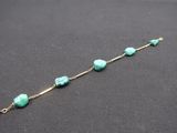 a close up of a bracelet with turquoise beads on a black surface