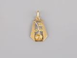 a close up of a gold plated pendant on a gray surface