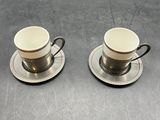 two cups and saucers sitting on top of a metal table