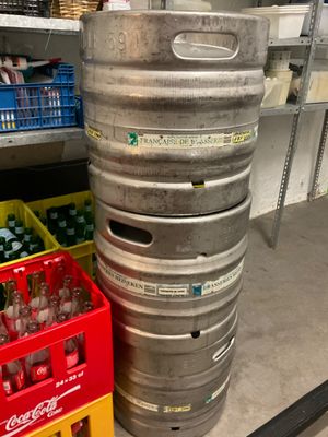 un grand fût de bière en métal posé à côté d'une caisse jaune