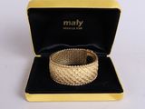 a close up of a gold bracelet in a box on a white surface
