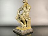 bronze statue of a man sitting on a pedestal with a hat on his head