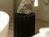 une pierre posée sur un socle dans une salle de bains, à côté d'une baignoire
