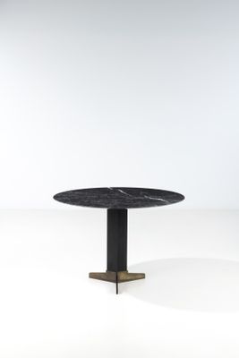 une table ronde avec un plateau en marbre noir sur fond blanc