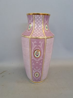 un vase rose orné d'une bordure dorée, posé sur une surface blanche
