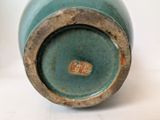 a blue vase with a brown lid sitting on a white surface