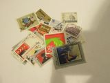a pile of stamps on a table with a person holding a cell phone