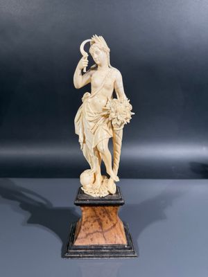 une figurine ancienne en ivoire sculpté représentant une femme tenant une fleur
