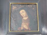 painting of a woman praying in a black frame with a gold border