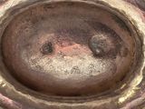 a close up of a silver vase with a face on it