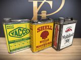 three vintage shell oil cans sitting on top of a wooden table
