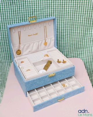 une petite boîte bleue contenant des bijoux, posée sur une table rose