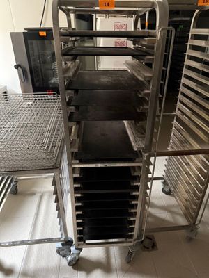 Plusieurs plateaux de nourriture sont posés sur un chariot métallique dans une cuisine