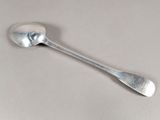 une cuillère en argent avec un manche de cuillère sur une surface blanche