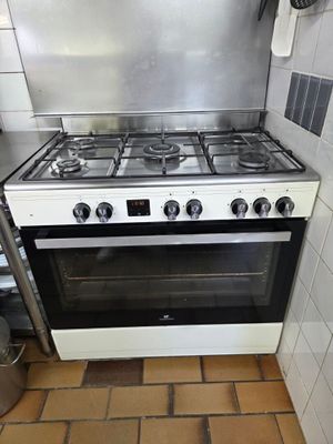 une cuisinière dans une petite cuisine, avec une casserole posée dessus