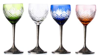 quatre verres à vin de couleurs différentes posés les uns à côté des autres sur une surface blanche