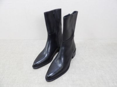 une paire de bottes en cuir noir posées sur une surface blanche