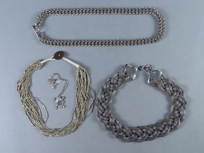 trois colliers et bracelets en argent posés sur un fond blanc