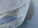 a close up of a car ' s front bumper with a dent on it