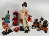 Plusieurs figurines représentant des femmes asiatiques sont exposées sur une surface blanche