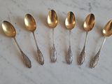 six silver spoons are lined up on a marble surface