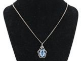 un collier avec une pierre bleue et une chaîne en argent sur un mannequin