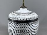 un vase noir et blanc surmonté d'une lampe