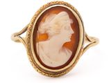 a close up of a gold ring with a cameo of a woman