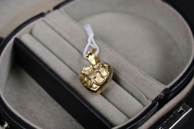 a gold necklace in a black case with a white ribbon