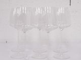 quatre verres à vin vides sont alignés sur une surface blanche