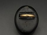 un gros plan sur un bouton noir orné d'une bande dorée