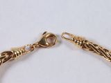 gold plated bracelet with a twisted design on a white background