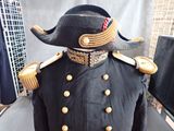 a black uniform with gold buttons and a black hat