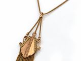 a close up of a gold necklace with a bird on it
