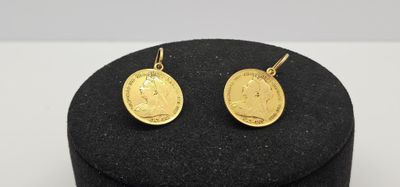 un gros plan sur une paire de boucles d'oreilles en or posées sur un chapeau noir