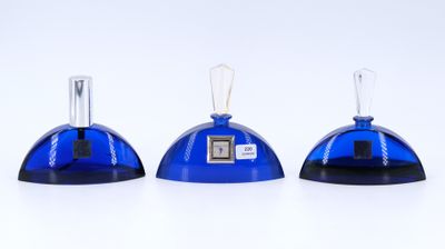 trois bouteilles en verre bleues surmontées d'une horloge, posées sur une surface blanche