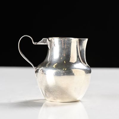 a silver pitcher sitting on a table with a black background