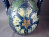 a blue and yellow vase with a flower on it