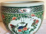 a green vase with a bird on it on a table