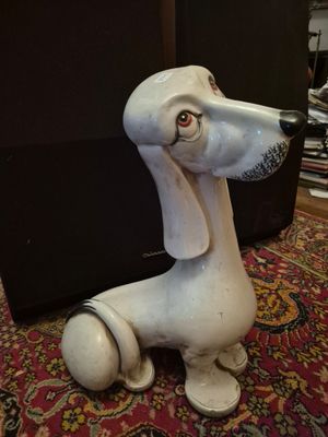 a white dog statue sitting on the floor next to a laptop