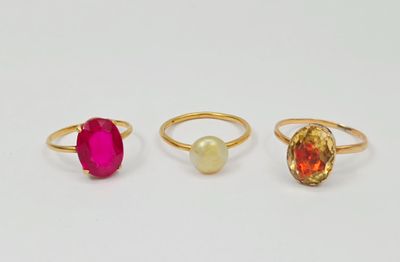 trois anneaux de couleurs différentes sur un fond blanc orné d'une perle
