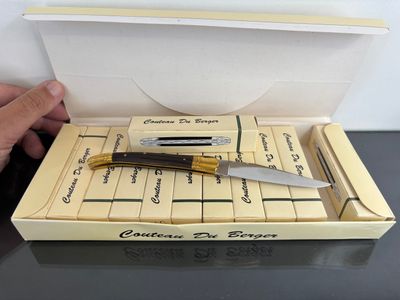 someone is holding a knife in a box on a table