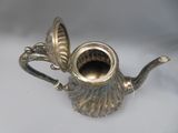 a silver teapot with a silver lid on a table