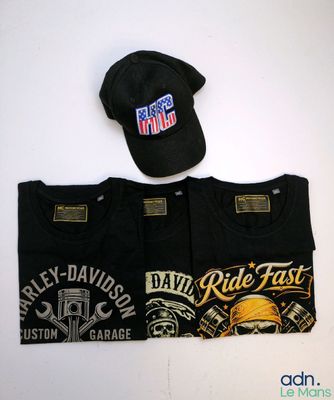 Deux t-shirts et une casquette sont posés sur une table