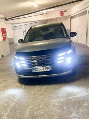 une voiture grise garée dans un parking couvert, tous phares allumés