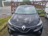 La voiture noire est garée sur le parking, à côté de la camionnette blanche.