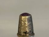 a silver thimble with a gold design on it
