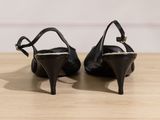 pair of black high heeled shoes sitting on top of a wooden table